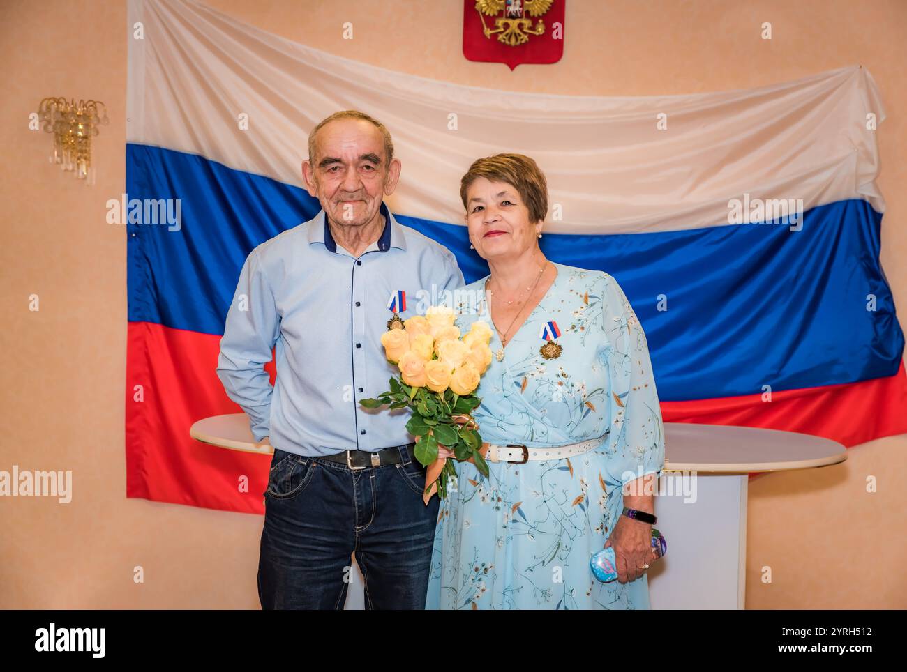 Ein russisches Paar feiert seinen goldenen Hochzeitstag im Standesamt. Das ältere Paar, beide über 70 Jahre alt, trägt stolz Medaillen, mit dem Stockfoto