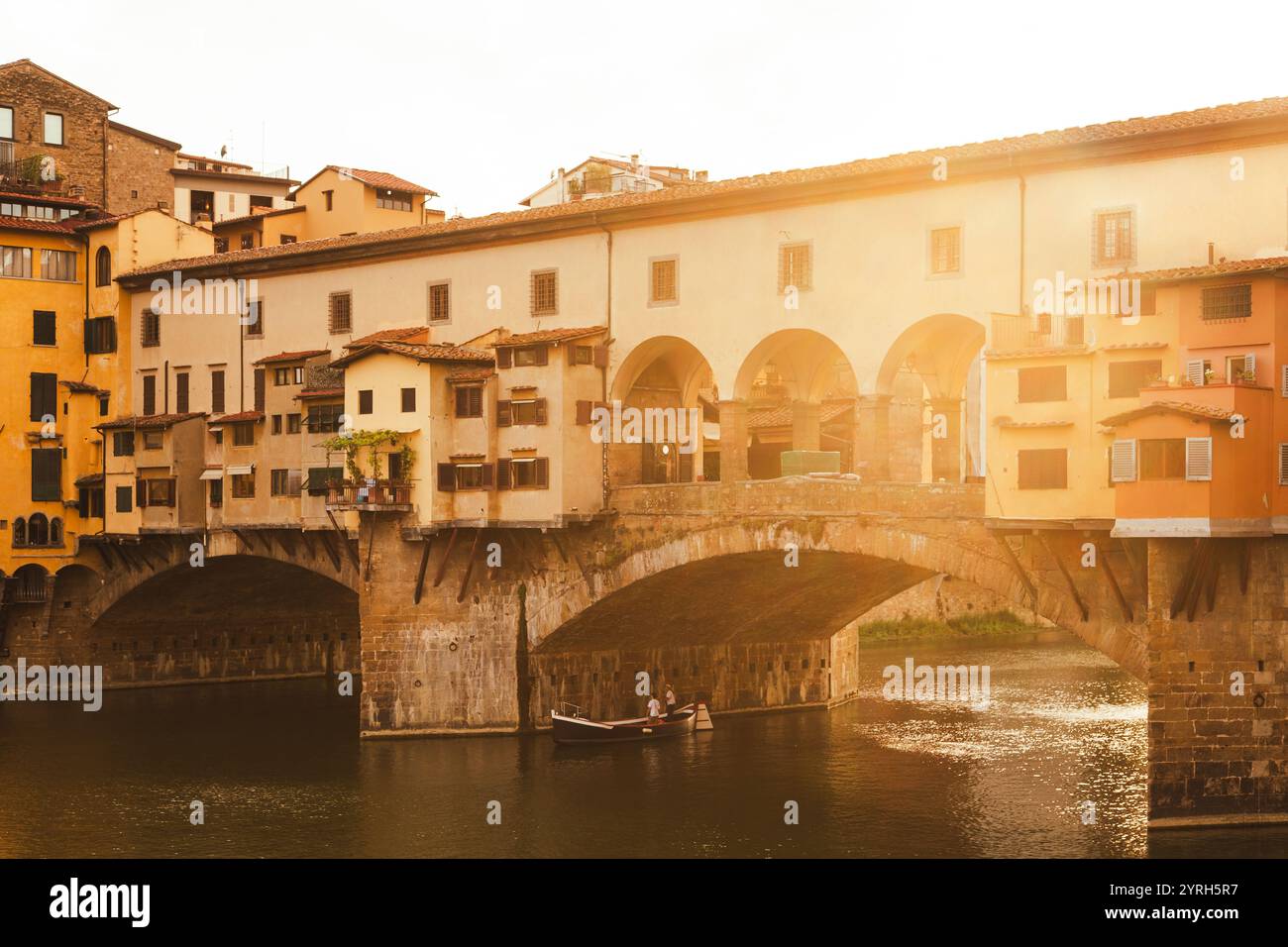 Die historische Brücke ponte vecchio in florenz leuchtet bei Sonnenuntergang und reflektiert auf dem Fluss arno und schafft eine malerische italienische Szene Stockfoto