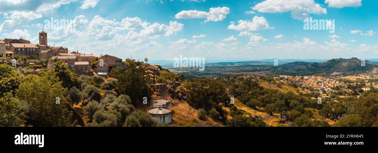 Monsanto historisches Dorf mit Granithäusern und einer Kirche, die die Landschaft in portugal dominiert, unter einem wunderschönen blauen Himmel mit weißen Wolken Stockfoto