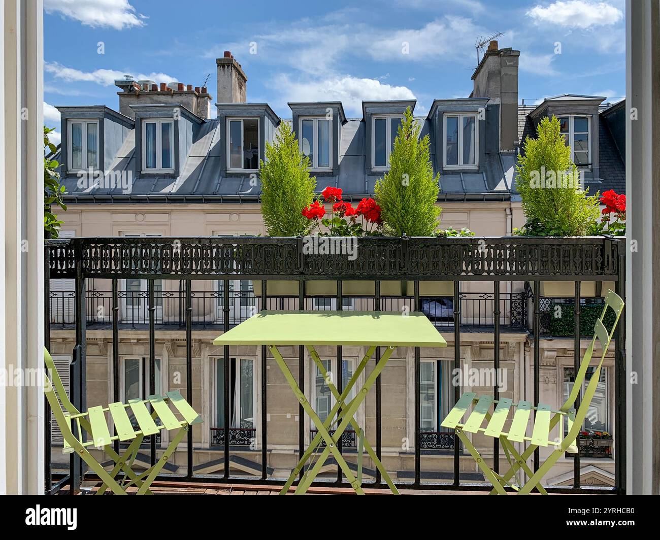 Pariser Apartment französischer Balkon, Blick auf die Fliesendächer von Paris mit den typischen Schornsteinen, Dachfenstern, frischen Blumen, französische Hauptstadt Stockfoto