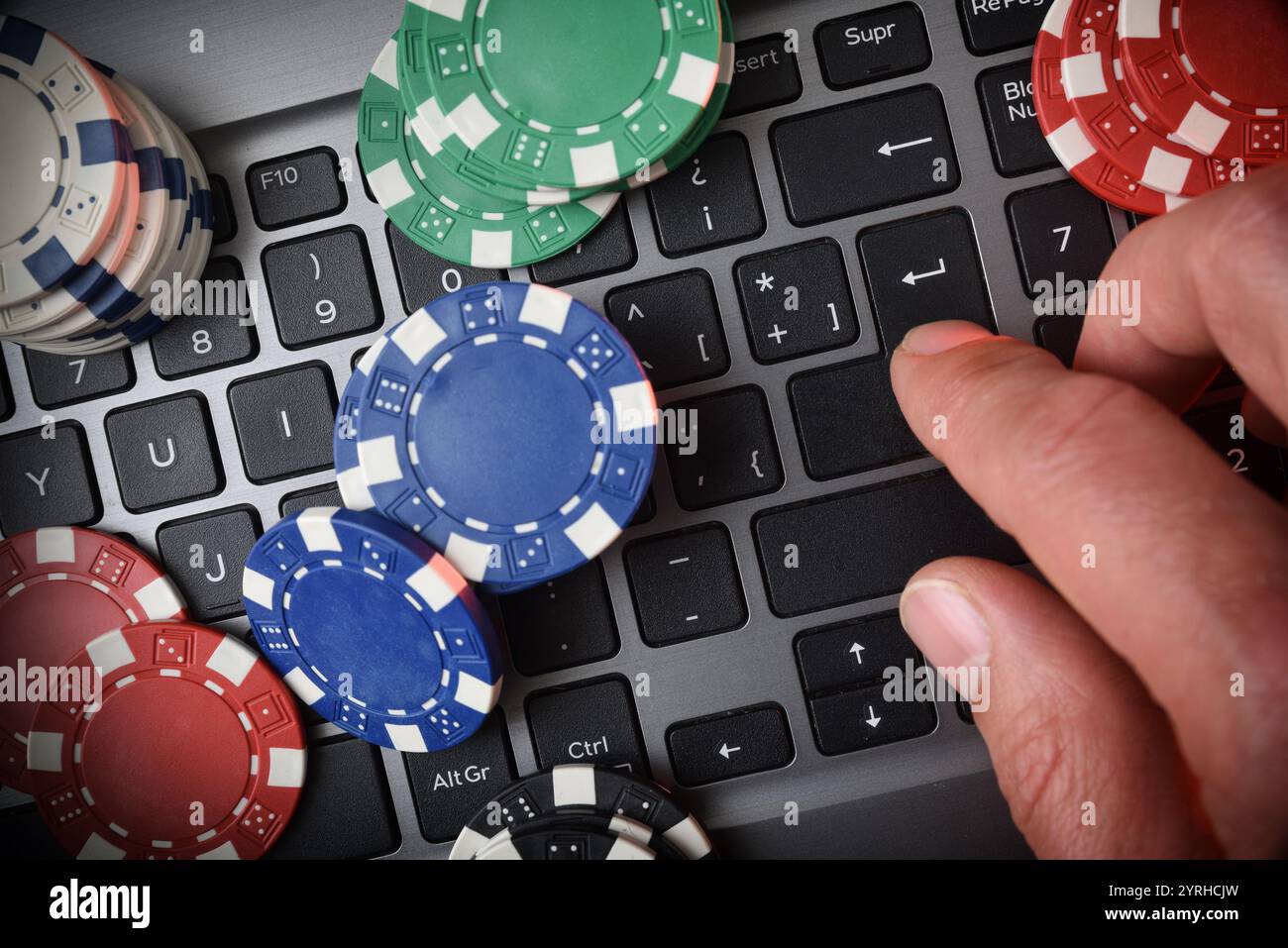 Online-Spiel-Wetten-Konzept mit Chips auf der Laptop-Tastatur und Hand-Drücken der ENTER-Taste. Draufsicht. Stockfoto