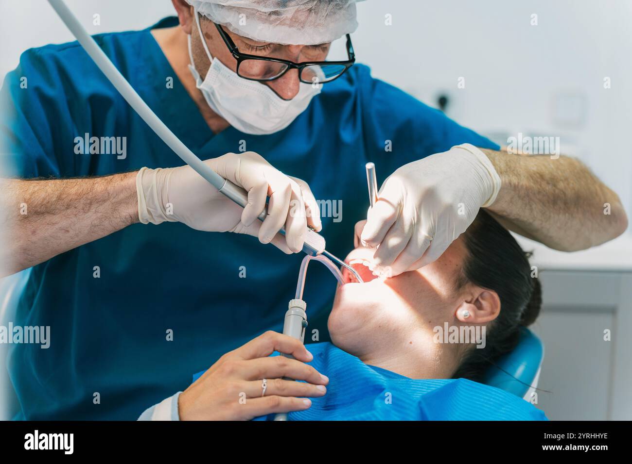 Zahnarzt in blauen Peelings mit professionellen Werkzeugen, während sich ein Patient auf einem Stuhl zurücklehnt, wobei Pflege und Präzision in A betont werden Stockfoto