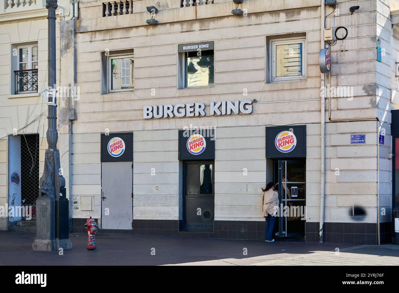 Marseille. Frankreich - 4. Dezember 2024: Dieses Foto zeigt den Haupteingang eines Burger King in einem alten Steingebäude. Das erkennbare sig Stockfoto