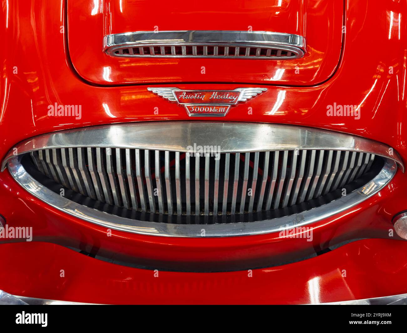 Nahaufnahme eines klassischen roten Austin Healey Sportwagens mit Emblem und verchromtem Kühlergrill - Smartphone-aufgenommenes Stockfoto
