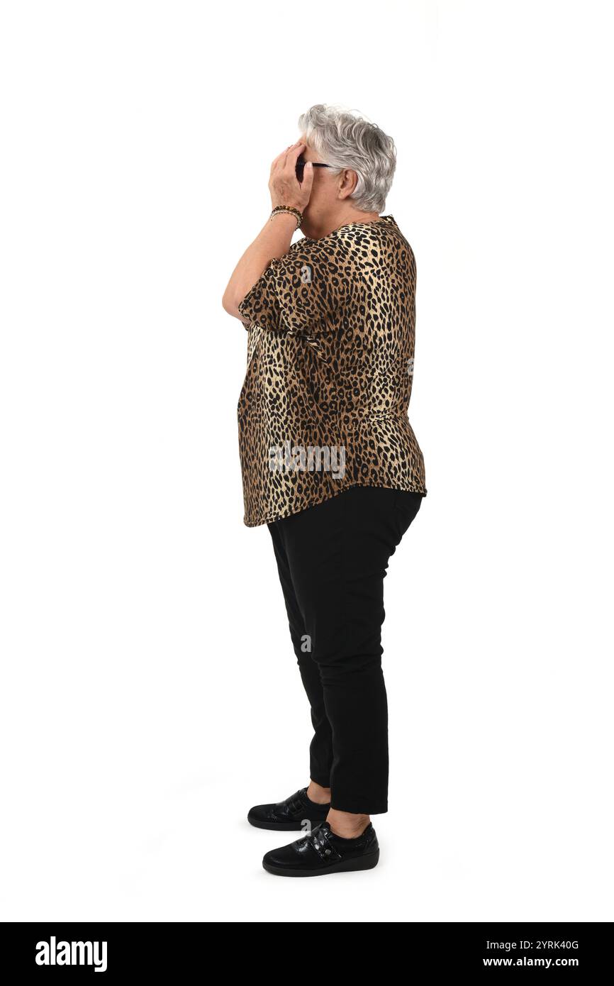 Seitenansicht einer älteren Frau, die ihr Gesicht mit ihrem Arm auf weißem Hintergrund bedeckt Stockfoto