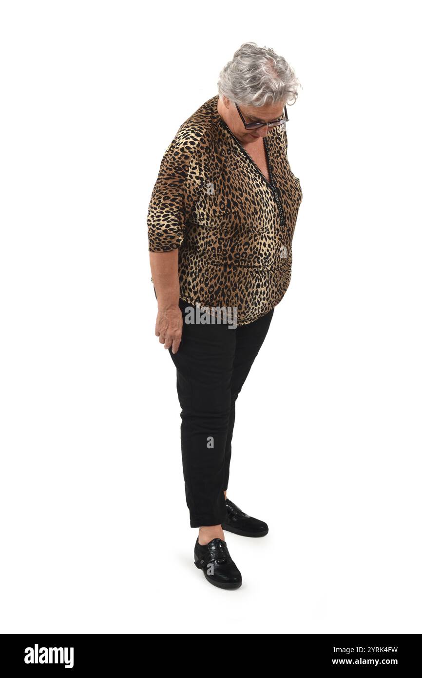 Die ältere Frau steht und blickt auf weißem Hintergrund nach unten Stockfoto