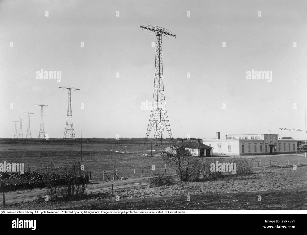 Radiosender in Grimeton. Funksender und -Empfänger für transatlantische Langwellen-Funktelegrafie. Der Bahnhof wurde im Dezember 1924 fertiggestellt. Der Standort im Dorf Grimeton außerhalb von Varberg in Südschweden wurde gewählt, weil er der beste Ort war, um ohne Hindernisse mit der Empfangsstation auf Long Island außerhalb von New York zu kommunizieren. Hier ist ein frühes Bild des Radiosenders, als er kürzlich in Betrieb genommen wurde. Die sechs Antennen und das Empfangsgebäude sind auf dem Bild aus den 1920er Jahren zu sehen Die gesamte Anlage, die sechs 127 Meter hohen Antennentürme sind präsent Stockfoto