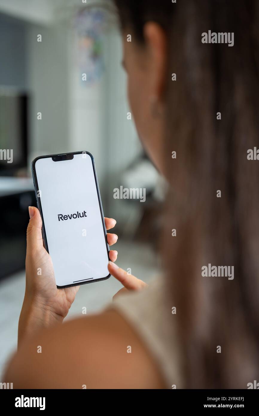 Prag, Tschechische republik - 2. Mai 2024: Frau mit iPhone mit dem Logo der Anwendung Revolute auf dem Bildschirm, mit der mobilen Anwendung für das Business Home Stockfoto