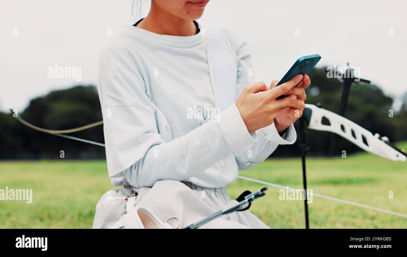Bogenschießen, Person oder Hände eines Bogenschützen mit Telefon für Training, soziale Medien oder Spiele im Freien. Pfeil, Schießstand oder Athlet mit Handy für SMS Stockfoto