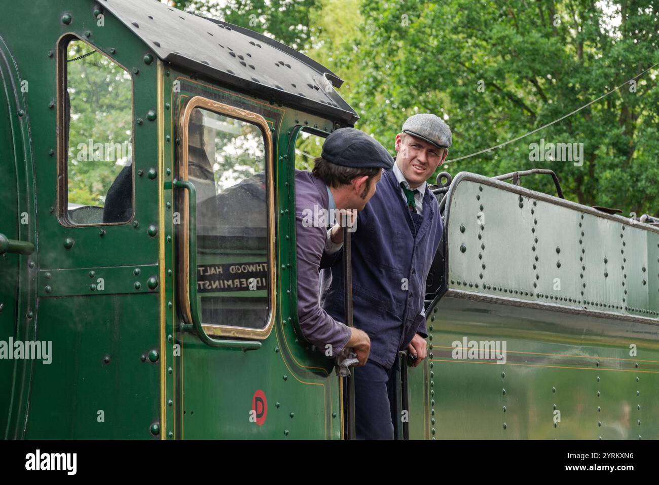 Severn Valley Railway, Arley, Worcestershire, 16-06-2019. Zwei Zugführer in Vintage-Uniformen warten, während die Passagiere an Bord der klassischen Dampflok steigen Stockfoto