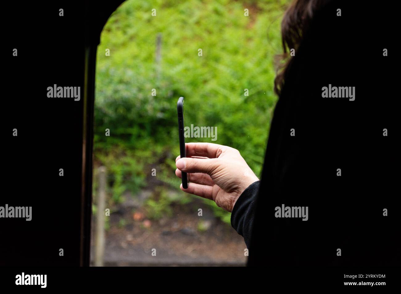 Severn Valley Railway, Bridgnorth, Shropshire, Worcestershire, 16-06-2019. Ein Passagier hält sein Handy aus dem Fenster, um einen besonderen Moment aufzuzeichnen. Stockfoto
