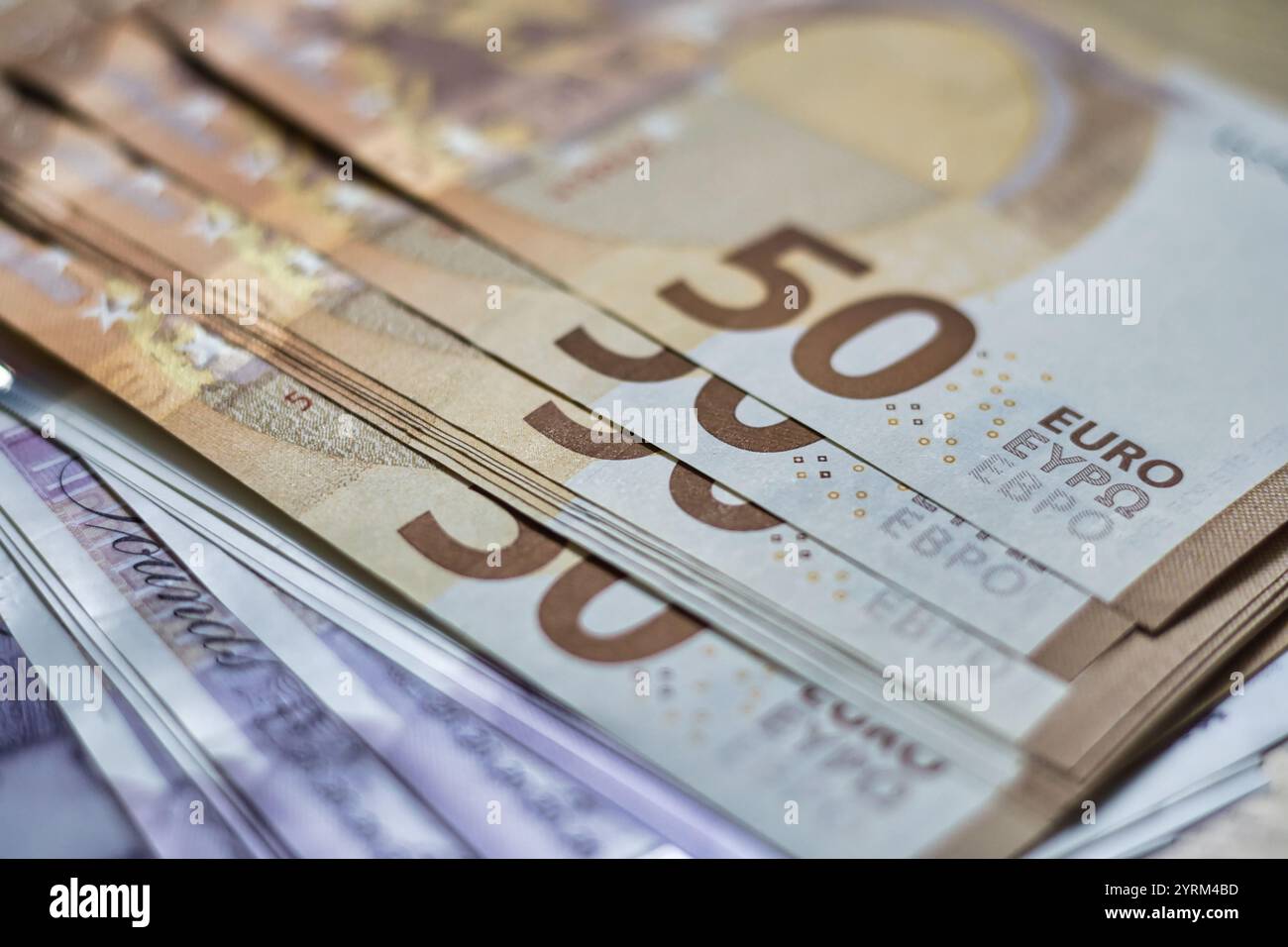 Nahaufnahme eines Stapels von fünfzig Euro-Banknoten mit der Nummer „50“. Andere Banknoten sind darunter zu sehen, was auf eine größere hindeutet Stockfoto