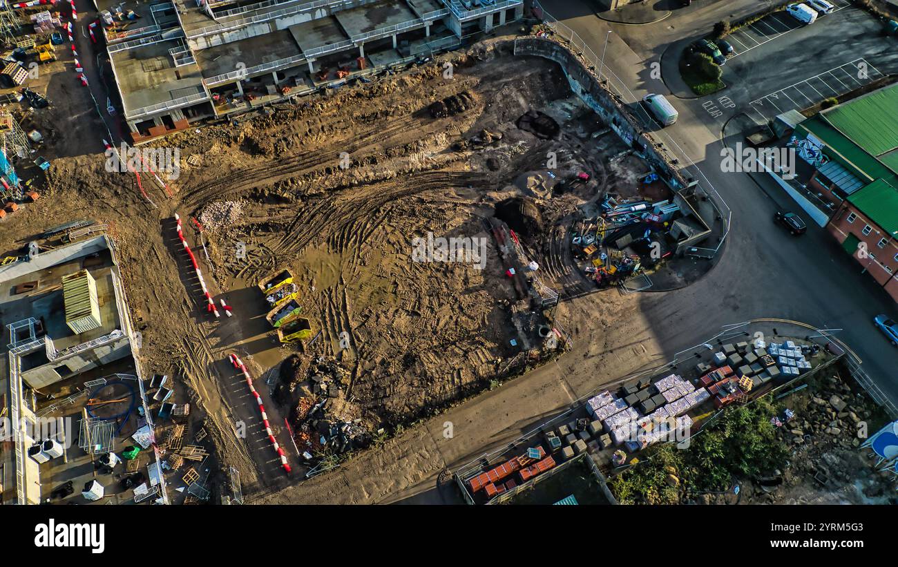 Luftaufnahme einer Baustelle. Das Zentrum ist von Baumaterialien, Maschinen und teilweise fertiggestelltem Bauwerk umgeben Stockfoto