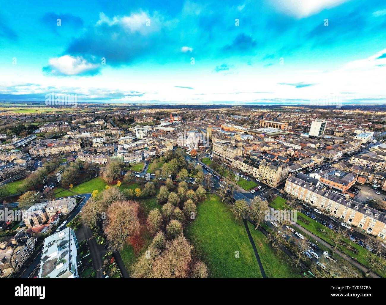 Aus der Vogelperspektive einer Stadt mit einer Mischung aus Wohn- und Geschäftsgebäuden, Straßen, Parks und einer lebhaften Stadtlandschaft unter teilweise bewölktem Himmel. T Stockfoto