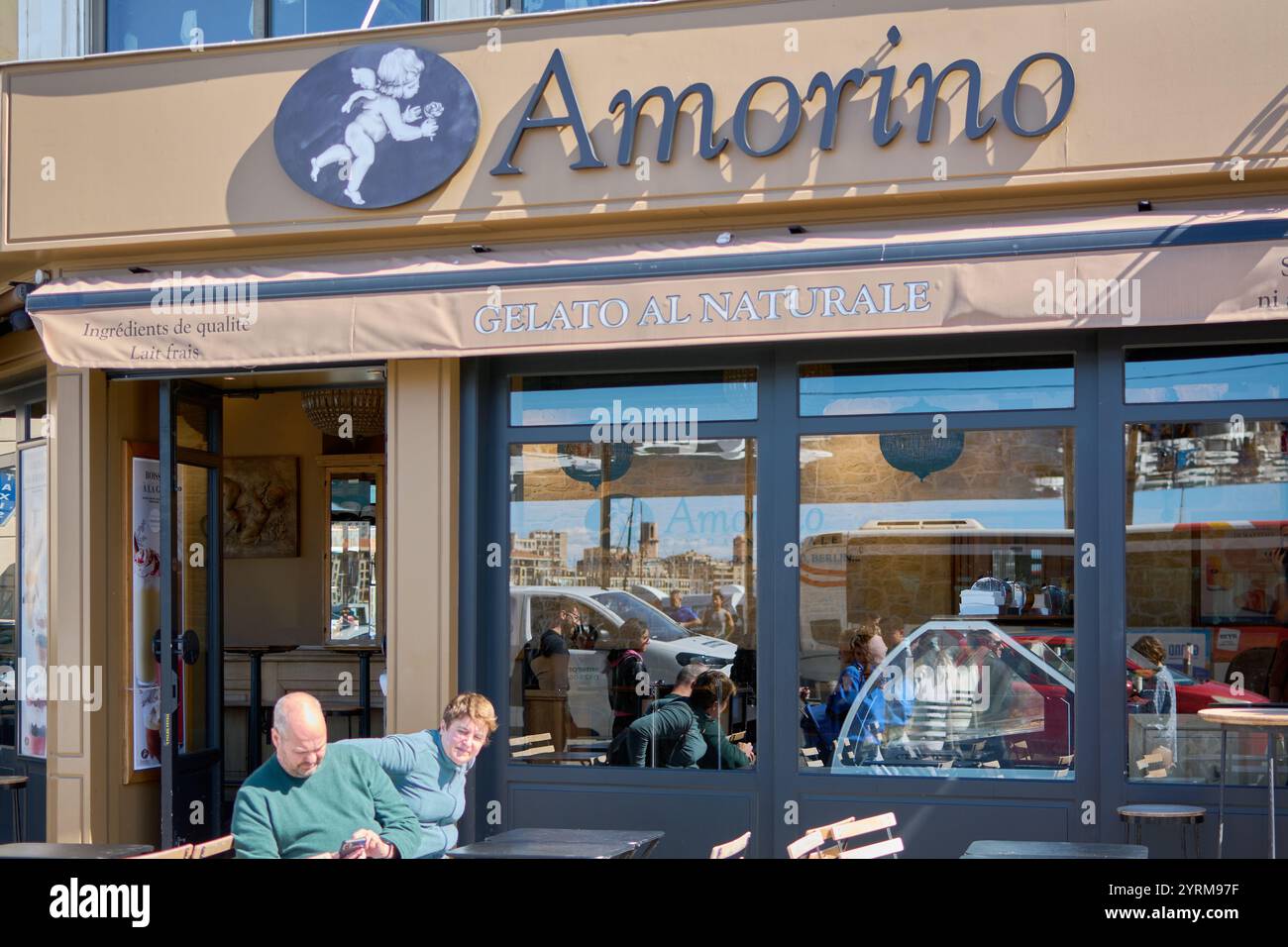 Marseille, Frankreich, 4. Dezember 2024: Sonniger Tag im Eisladen Amorino. Gäste genießen Leckereien im Freien. Die Ladenfront zeigt das Amorino-Logo und Gelato al Stockfoto