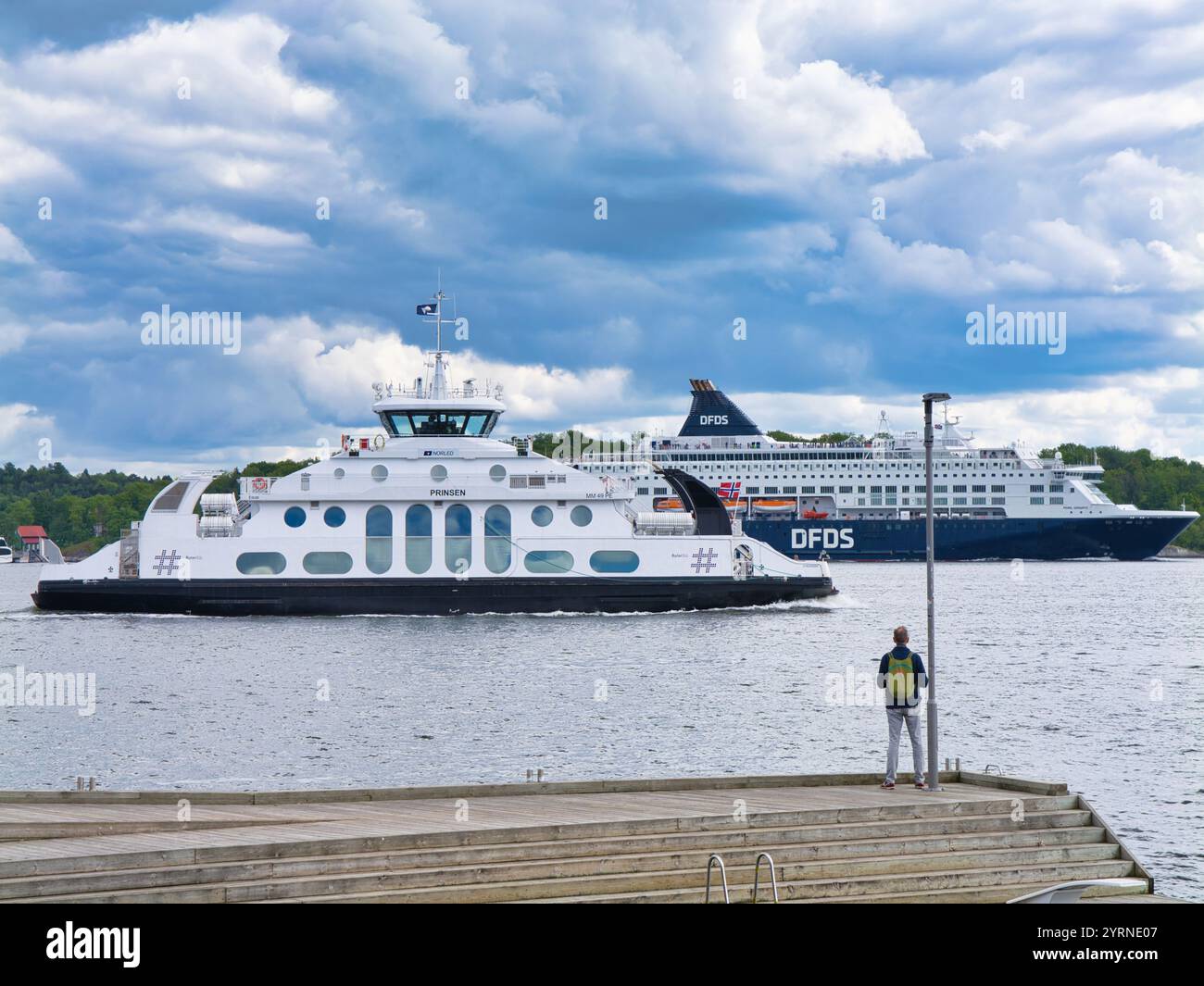 Oslo, Norwegen – 12. Juni 2024: Ein Zuschauer beobachtet die elektrische Passagierfähre MS Prinsen (im Vordergrund) und die DFDS MS Pearl Seaways, die in Oslo Fjo vorbeifahren Stockfoto