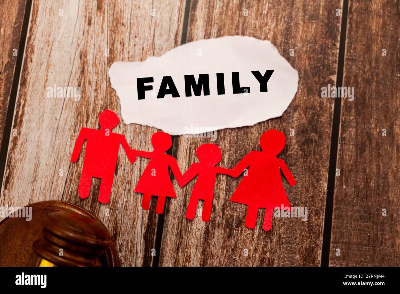 Papierfamilienkette, Hammer und „Familie“-Text auf Holz. Konzepte des Familienrechts, des Sorgerechts, der Scheidung und des Rechtswesens. Stockfoto