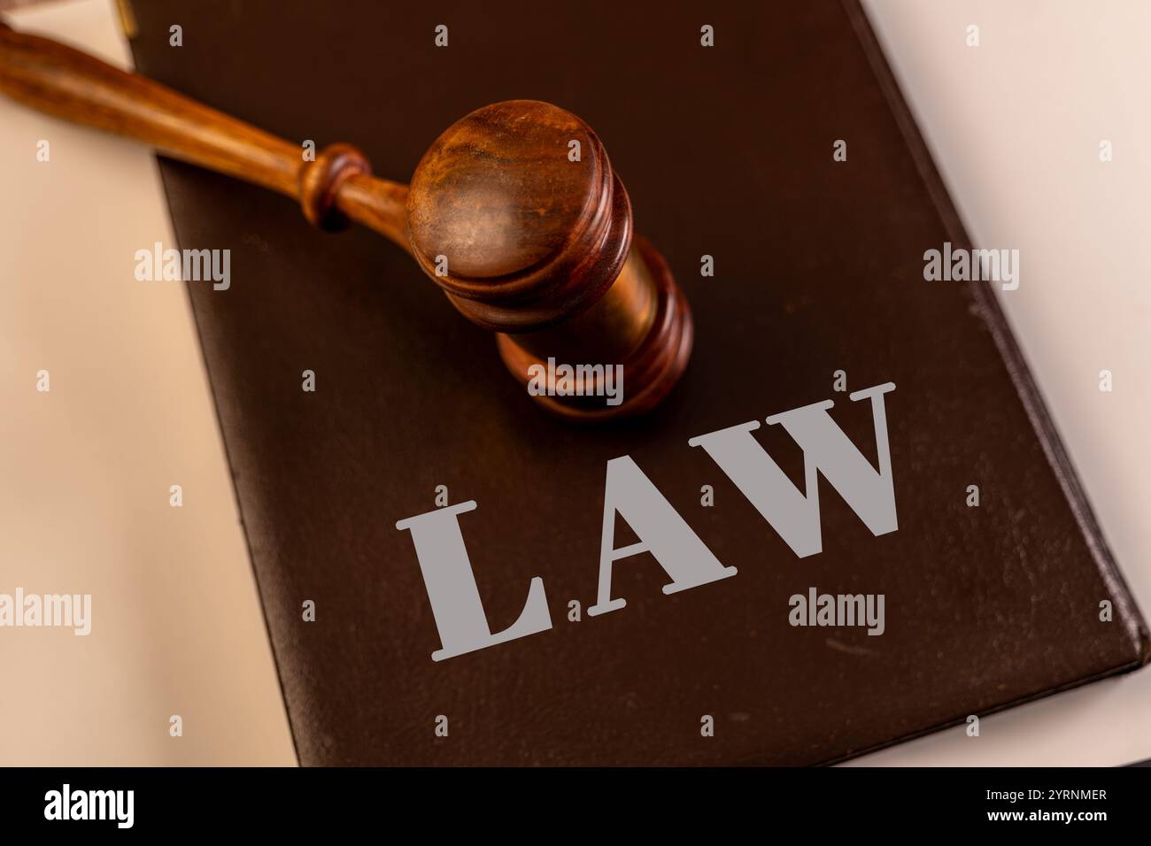 Ein hölzerner Hammer, der auf einem Gesetzbuch steht und Gerechtigkeit, Legalität und Gerichtsentscheidungen symbolisiert. Ideal für rechtliche oder pädagogische Inhalte. Stockfoto