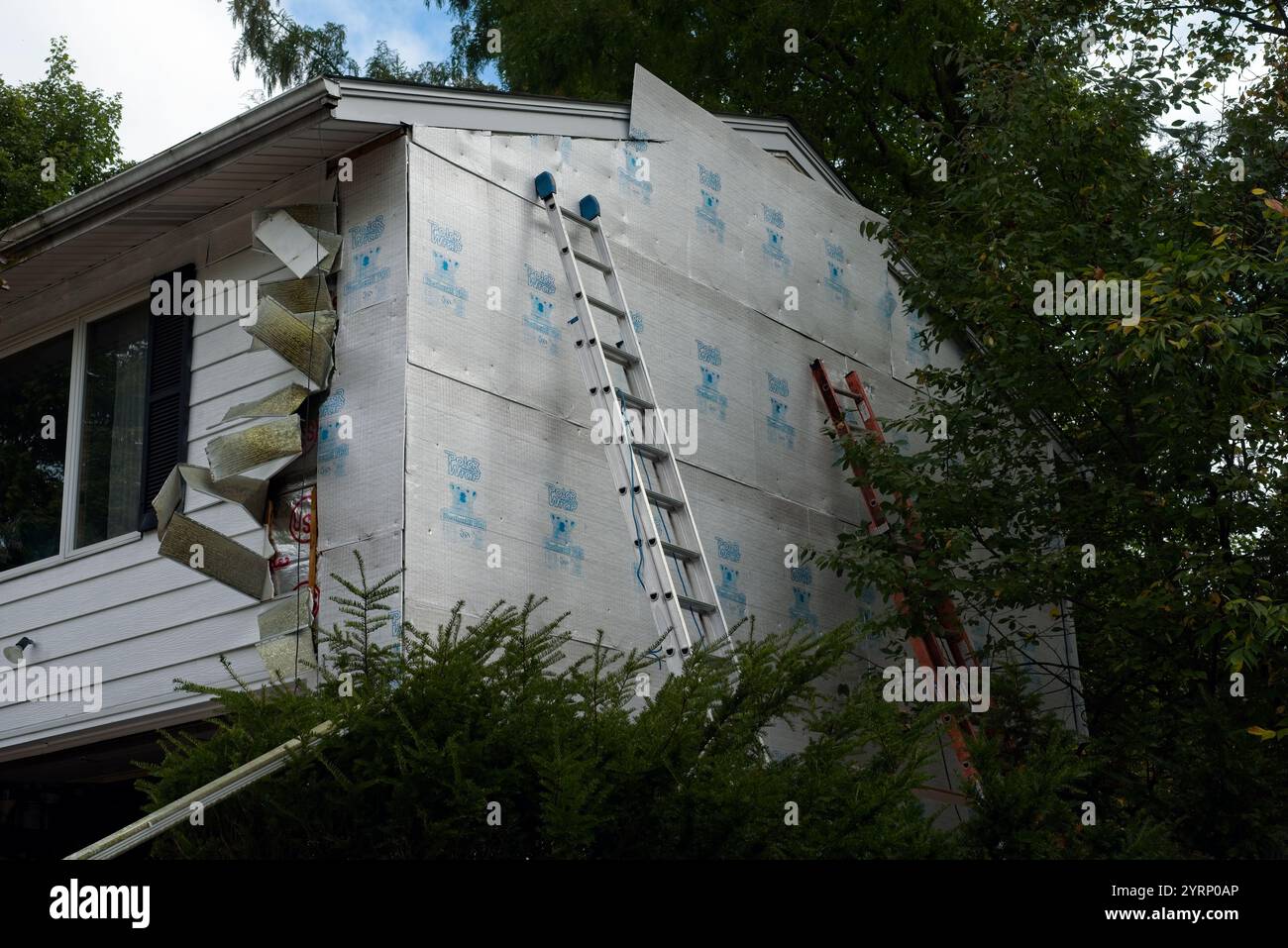 Alte Aluminiumverkleidungen werden von der Vorderseite eines Hauses im Nordosten von Ohio entfernt, während die angrenzende Seite mit neuen Dämmplatten ausgestattet ist. Stockfoto