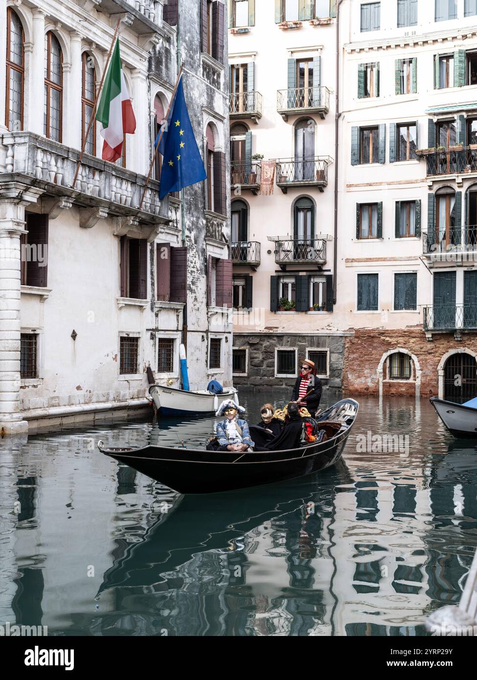 Touristen auf einer Gondelfahrt entlang eines Wasserkanals auf den Straßen von Venedig, Italien Stockfoto