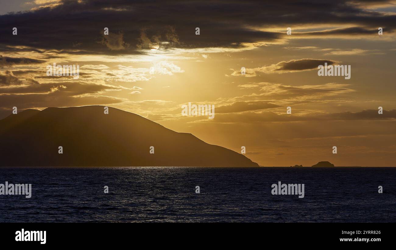 Der Himmel zeigt einen dramatischen Sonnenuntergang mit dunklen Wolken und einer Insel am Horizont, Sonnenuntergang, Kassos, Karpathos, vorgelagerte Inseln, Dodekanesisch, Griechische Inseln Stockfoto