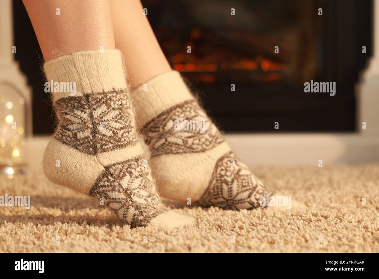 Eine Frau in warmen Socken ruht sich zu Hause am Kamin aus, schließt Stockfoto