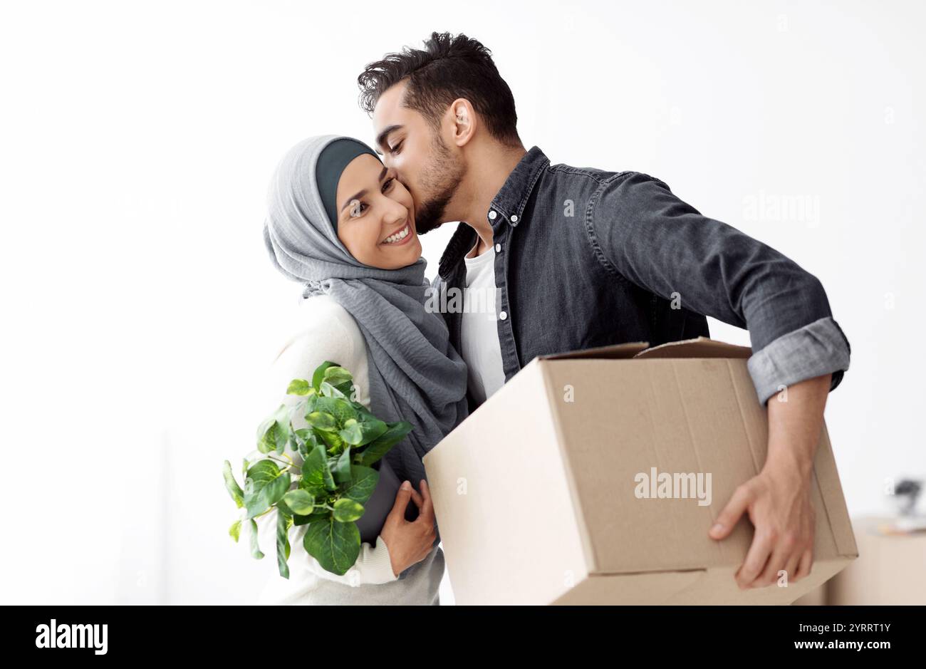 Gutaussehender Kerl, der seine glückliche Frau küsst und zusammen zieht Stockfoto
