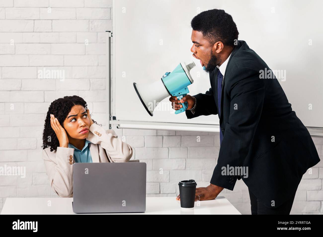 Wütender Boss mit Lautsprecher schreit weibliche Untergebene im Büro an Stockfoto