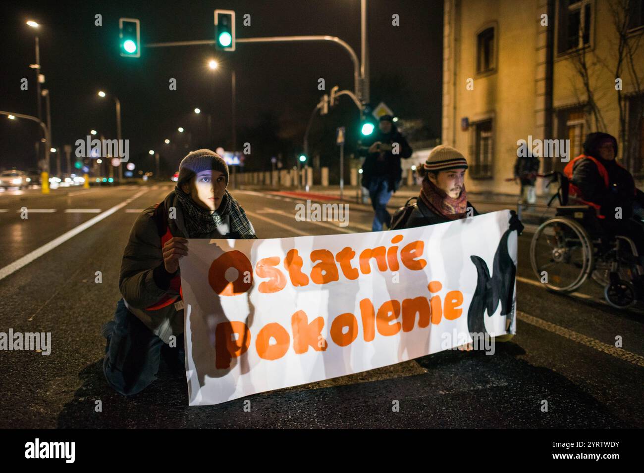 Demonstranten der Organisation der letzten Generation, die ein Banner halten, blockieren die Straße während einer Demonstration gegen den polnischen Premierminister Donald Tusks Klimapolitik. Aktivisten der Klimabewegung der letzten Generation (Ostatnie Pokolenie) haben seit vergangener Woche eine lang andauernde Kampagne zur Blockierung wichtiger Routen während der Hauptverkehrszeiten gestartet, wobei sich einige Demonstranten an die Straßen kleben. Sie fordern, dass alle Mittel für neue Schnellstraßen- und Autobahnprojekte stattdessen auf die Verbesserung des öffentlichen Verkehrs ausgerichtet werden und dass billige Monatskarten für die Nutzung des öffentlichen Verkehrs eingeführt werden Stockfoto