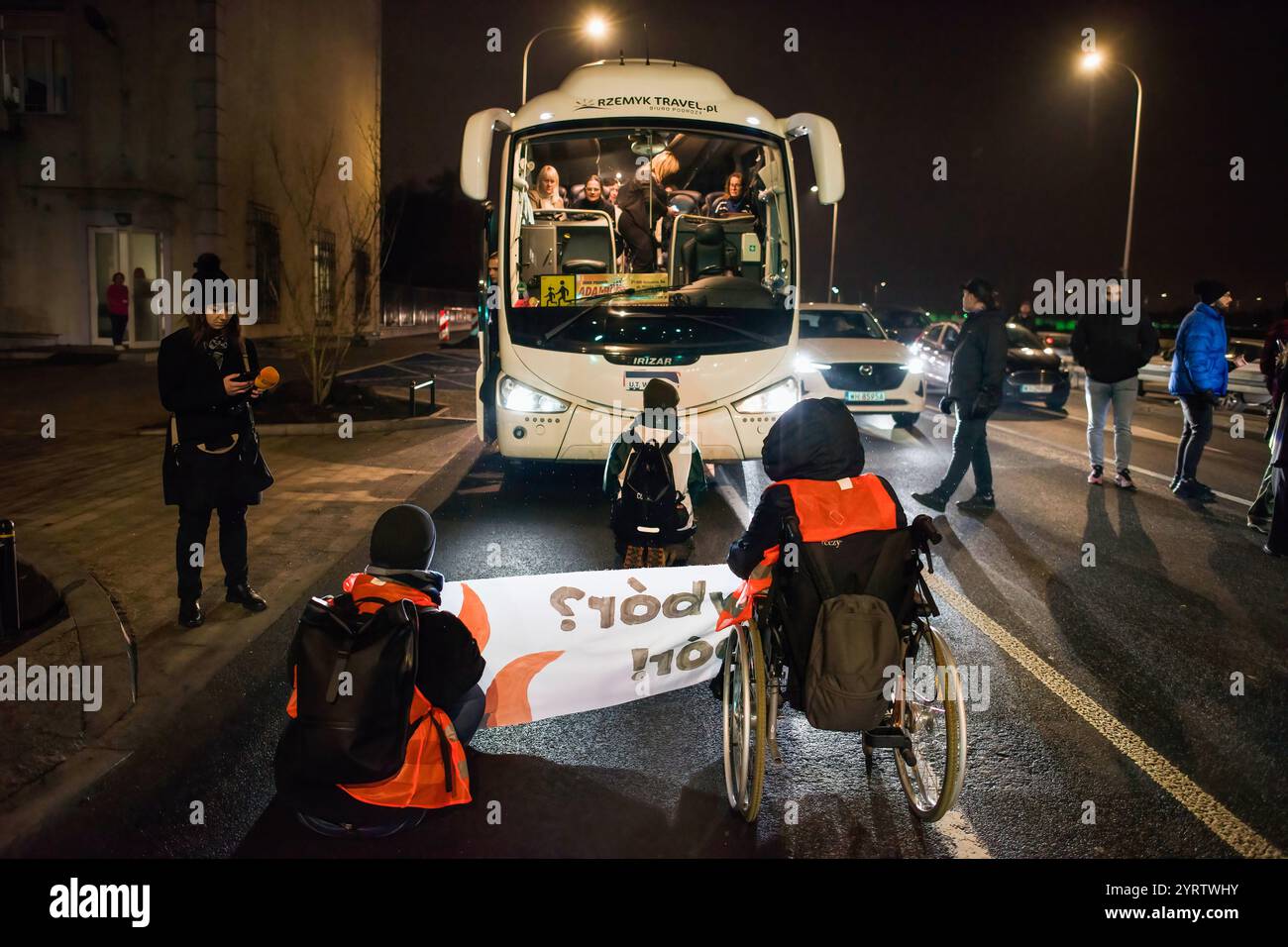 Demonstranten der Organisation der letzten Generation, die ein Banner halten, blockieren die Straße während einer Demonstration gegen den polnischen Premierminister Donald Tusks Klimapolitik. Aktivisten der Klimabewegung der letzten Generation (Ostatnie Pokolenie) haben seit vergangener Woche eine lang andauernde Kampagne zur Blockierung wichtiger Routen während der Hauptverkehrszeiten gestartet, wobei sich einige Demonstranten an die Straßen kleben. Sie fordern, dass alle Mittel für neue Schnellstraßen- und Autobahnprojekte stattdessen auf die Verbesserung des öffentlichen Verkehrs ausgerichtet werden und dass billige Monatskarten für die Nutzung des öffentlichen Verkehrs eingeführt werden Stockfoto