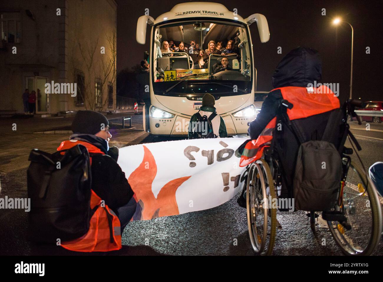 Demonstranten der Organisation der letzten Generation, die ein Banner halten, blockieren die Straße während einer Demonstration gegen den polnischen Premierminister Donald Tusks Klimapolitik. Aktivisten der Klimabewegung der letzten Generation (Ostatnie Pokolenie) haben seit vergangener Woche eine lang andauernde Kampagne zur Blockierung wichtiger Routen während der Hauptverkehrszeiten gestartet, wobei sich einige Demonstranten an die Straßen kleben. Sie fordern, dass alle Mittel für neue Schnellstraßen- und Autobahnprojekte stattdessen auf die Verbesserung des öffentlichen Verkehrs ausgerichtet werden und dass billige Monatskarten für die Nutzung des öffentlichen Verkehrs eingeführt werden Stockfoto