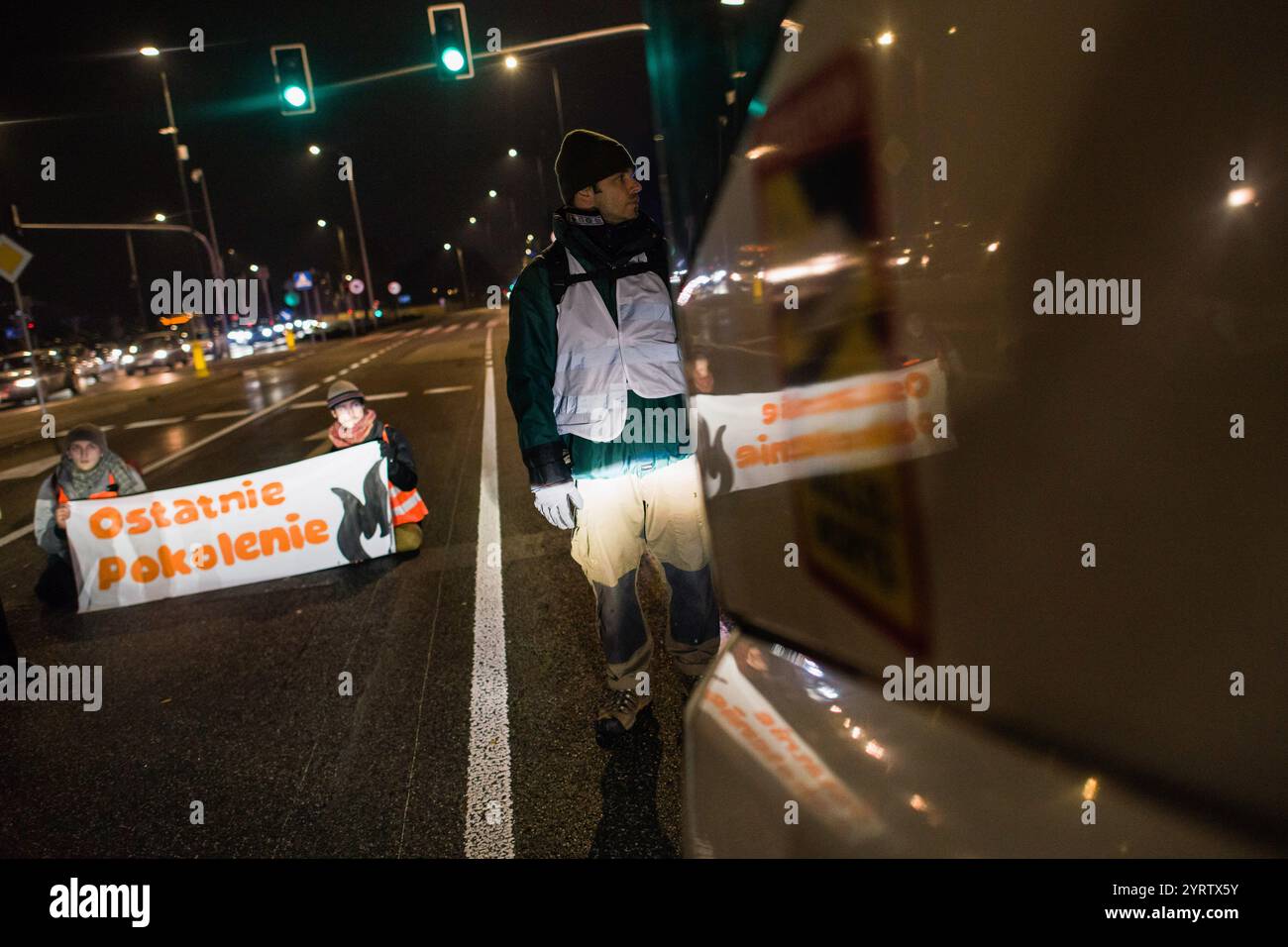 Demonstranten der Organisation der letzten Generation, die ein Banner halten, blockieren die Straße während einer Demonstration gegen den polnischen Premierminister Donald Tusks Klimapolitik. Aktivisten der Klimabewegung der letzten Generation (Ostatnie Pokolenie) haben seit vergangener Woche eine lang andauernde Kampagne zur Blockierung wichtiger Routen während der Hauptverkehrszeiten gestartet, wobei sich einige Demonstranten an die Straßen kleben. Sie fordern, dass alle Mittel für neue Schnellstraßen- und Autobahnprojekte stattdessen auf die Verbesserung des öffentlichen Verkehrs ausgerichtet werden und dass billige Monatskarten für die Nutzung des öffentlichen Verkehrs eingeführt werden Stockfoto