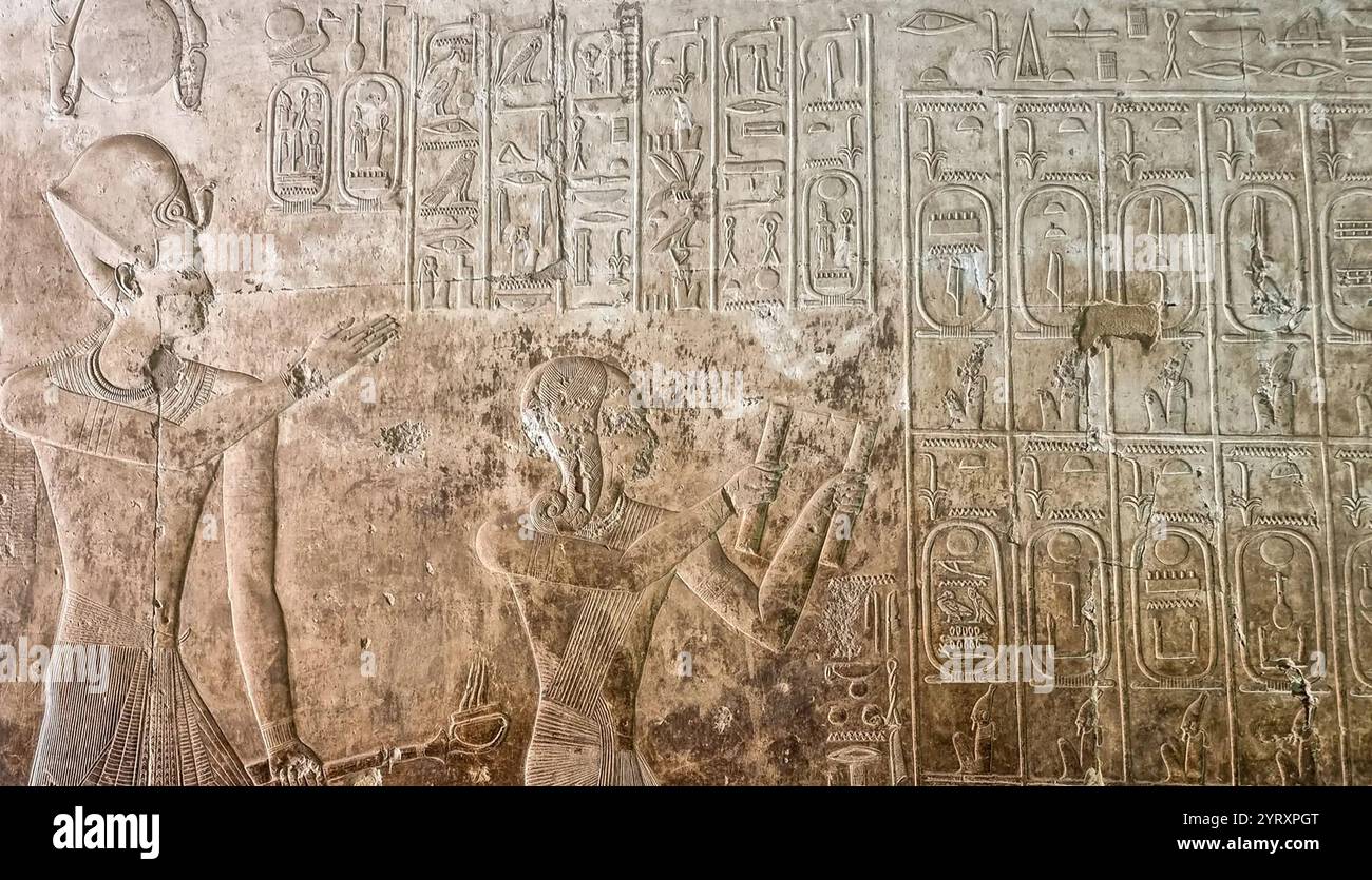Die Abydos King List enthält die Namen von 76 Königen des alten Ägypten. Sie wurde an einer Wand des Tempels von Seti I. in Abydos, Ägypten, gefunden. Sie besteht aus drei Reihen mit 38 Kartuschen (Umrandungen, die den Namen eines Königs umschließen) in jeder Zeile. Die oberen beiden Reihen enthalten die Namen der Könige, während die dritte Reihe lediglich den Namen und das Nomen von Seti I. wiederholt. Das Relief zeigt Seti I. und seinen Sohn Ramesses II. Auf dem Weg zu einer Opfergabe an Ptah Seker Osiris im Namen ihrer 72 Vorfahren: Der Inhalt der Königsliste. Ramesses ist dargestellt, der Räuchergefäße hält. Stockfoto