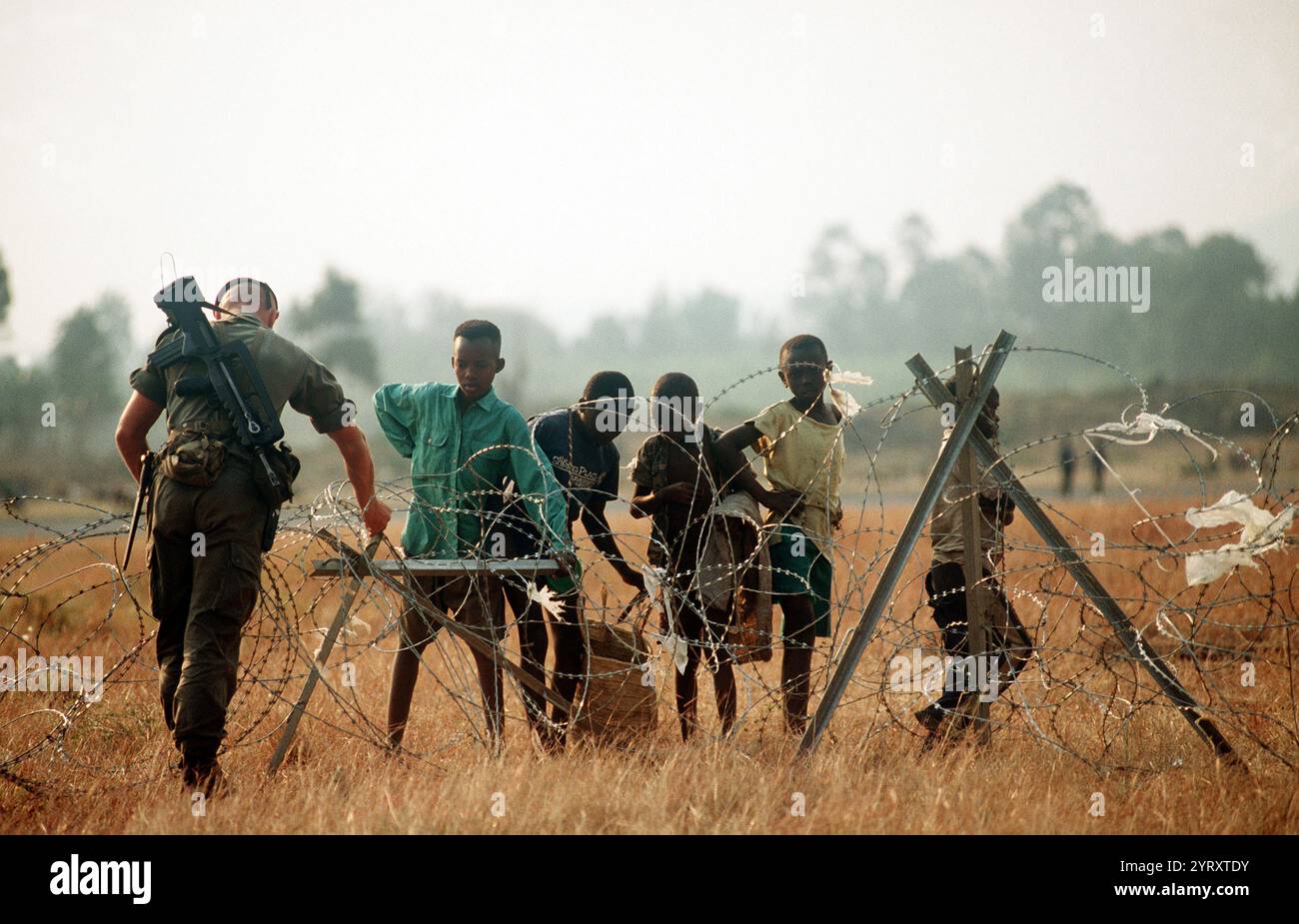 Ruandischer Bürgerkrieg: 1994. Ein französischer Soldat, einer der internationalen Truppen, die die Hilfsbemühungen für ruandische Flüchtlinge unterstützen, justiert den Concertina-Draht um den Flughafen. (Veröffentlicht) Stockfoto