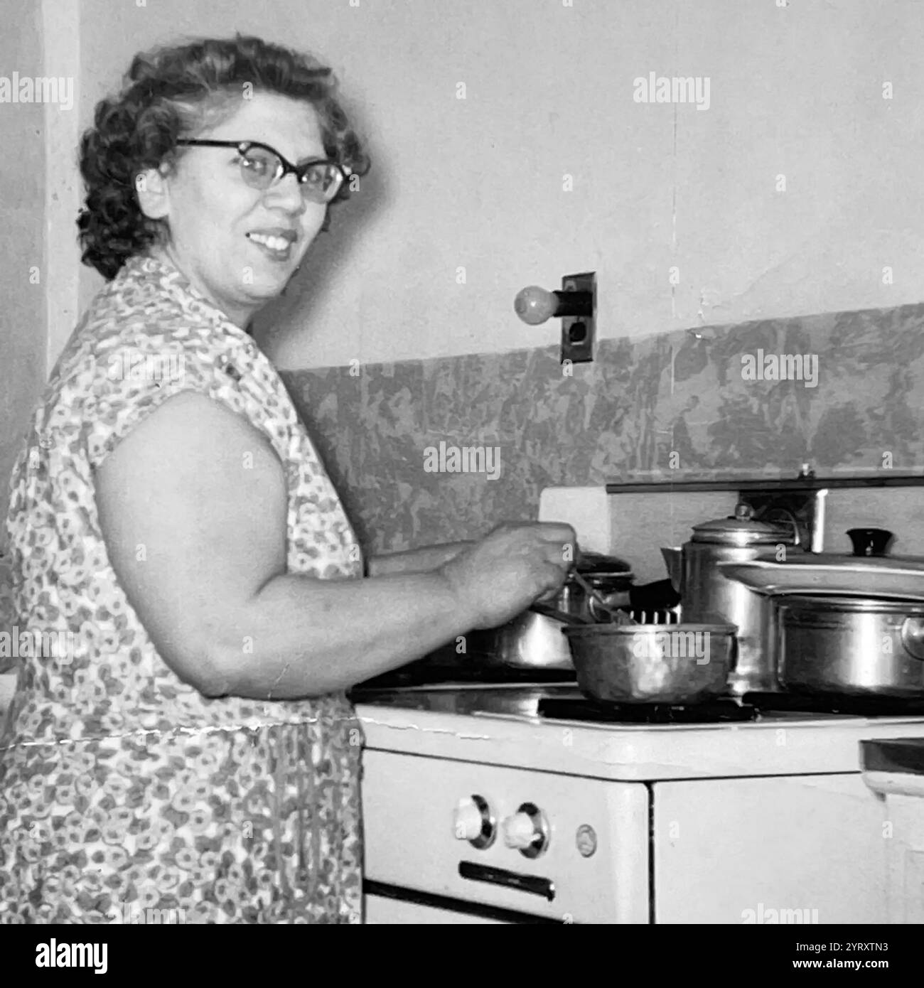 1955 heimische Szene als Brite. Mutter bereitet Essen auf einem Herd zu. Stockfoto