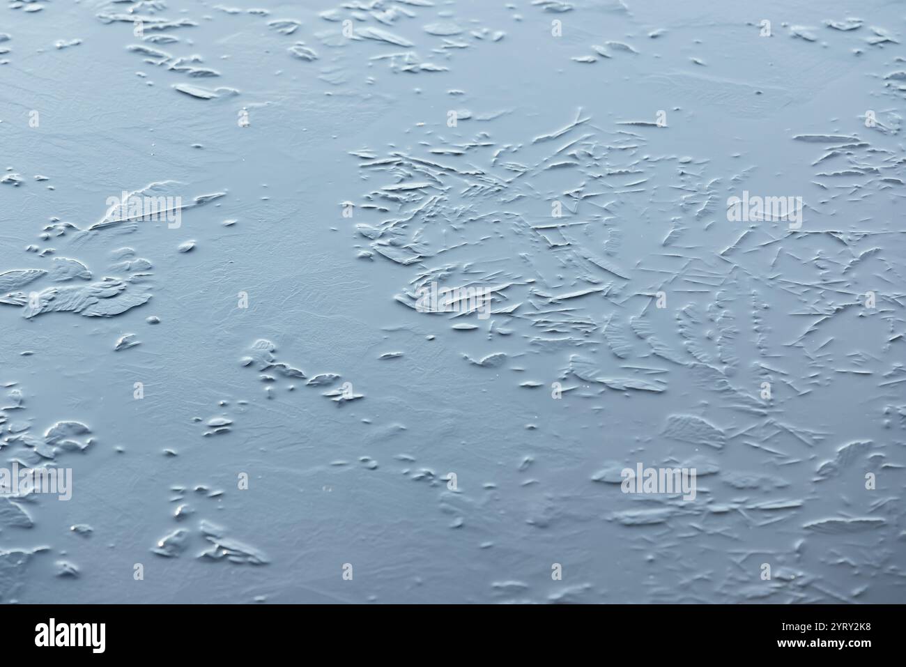 Dünne Eisschicht auf einem gefrorenen See, natürliches Winterhintergrundfoto mit selektivem Fokus Stockfoto