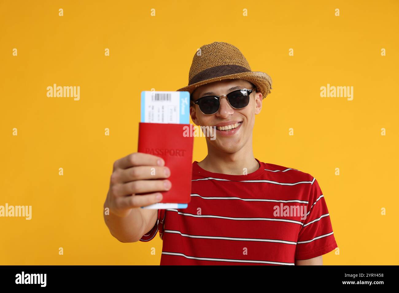 Glücklicher Reisender in Sonnenbrille mit Pass und Ticket auf gelbem Hintergrund Stockfoto