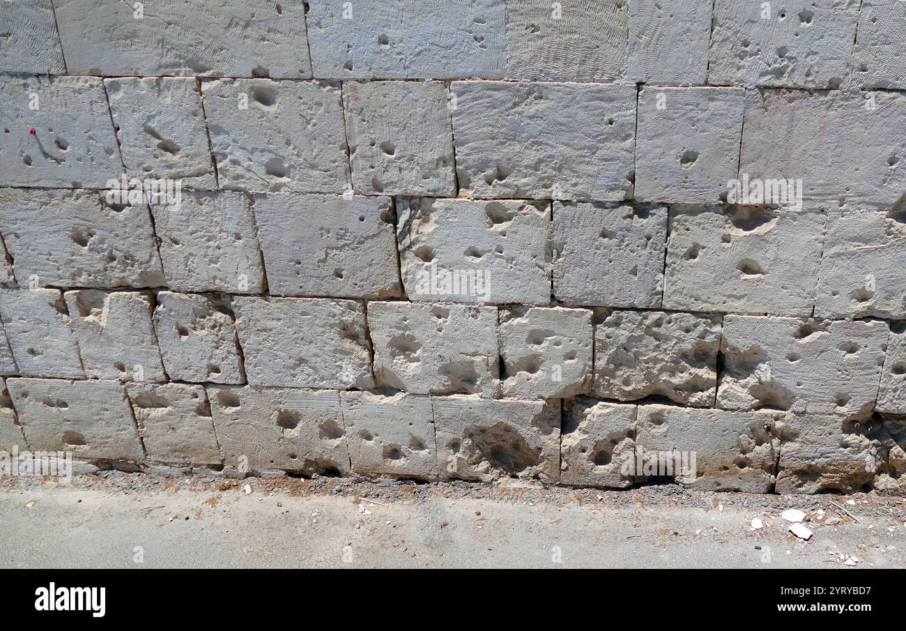 Bullet Marks in der Mauer der Heiligen Dreifaltigkeit Kathedrale (Russisch-orthodoxe Kirche in Jerusalem) wurde 1860–1872 von einem palästinensischen russisch-orthodoxen Institut errichtet, das in Jerusalem unter der Regierung des Osmanischen Reiches betrieben wurde. Das Bauwerk wurde vom Architekten Martin Eppinger als Basilika mit zwei Gängen und abgerundeten Kammern an der Seite entworfen, die den Dom kreuzförmig machen. Die Kathedrale ist aus weißem Stein gebaut. Während des ersten arabisch-israelischen Krieges wurde der Tempel schwer beschädigt. Ab 1948 ist es in der Gerichtsbarkeit der Russisch-Orthodoxen Kirche Stockfoto