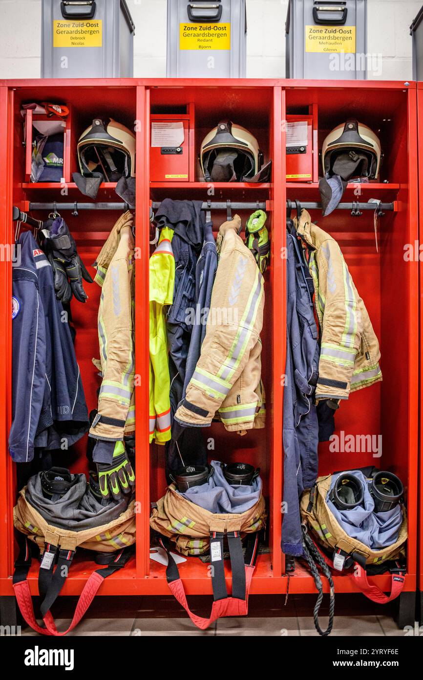 Feuerwehrausrüstung, die ordentlich in roten Schließfächern angeordnet ist, mit Helmen, Jacken, Handschuhen und Sicherheitsausrüstung für den Notfall. Stockfoto
