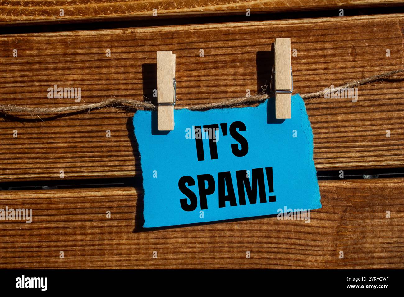 Es ist eine Spam-Nachricht, geschrieben auf zerrissenem blauem, zerrissenem Papierstück mit hölzernem Hintergrund. Konzeptionell ist das Spam-Symbol. Kopierbereich. Stockfoto