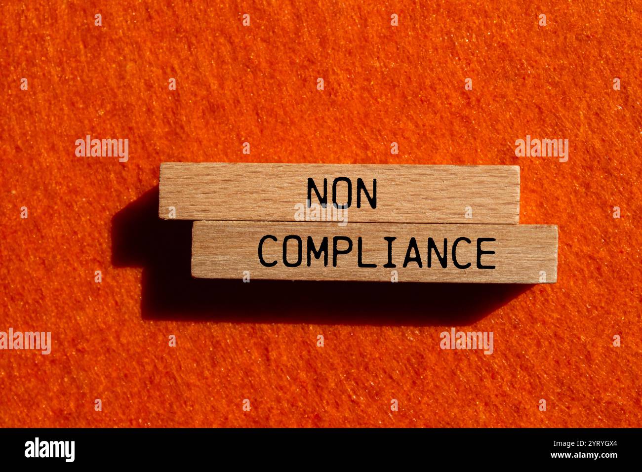 Meldung über Nichteinhaltung auf Holzblöcken mit orangefarbenem Hintergrund. Symbol für konzeptionelle Nichteinhaltung. Kopierbereich. Stockfoto