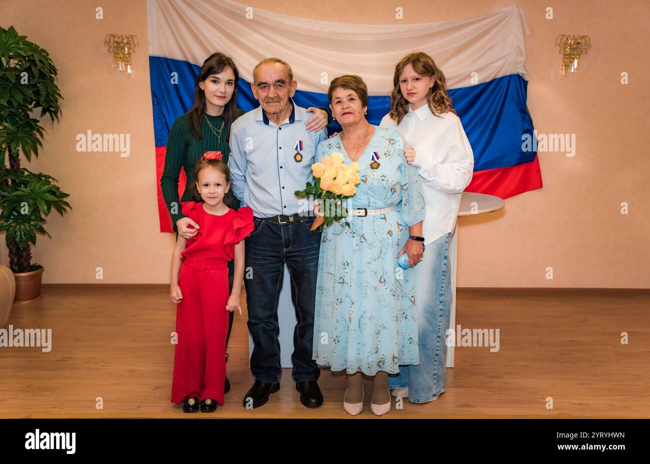 Eine russische Familie feiert einen goldenen Hochzeitstag (50 Jahre). Die Großeltern sind elegant gekleidet und von ihren Enkeln Smili umgeben Stockfoto