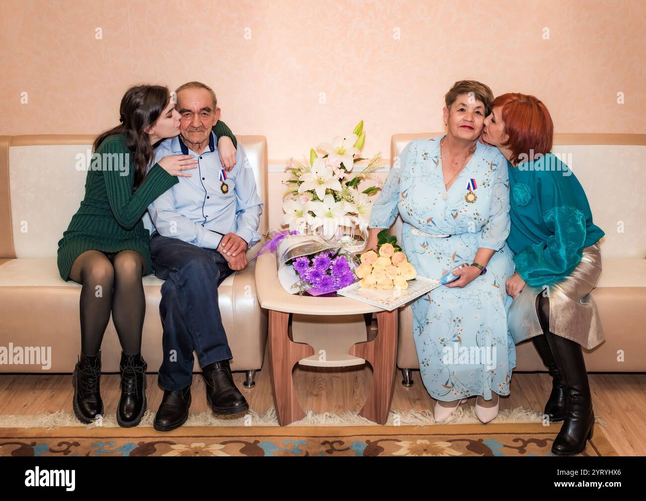 Eine russische Familie feiert einen goldenen Hochzeitstag in einem Standesamt. Ehemann und Ehefrau sitzen zusammen mit Medaillen, umgeben von ihrer dau Stockfoto