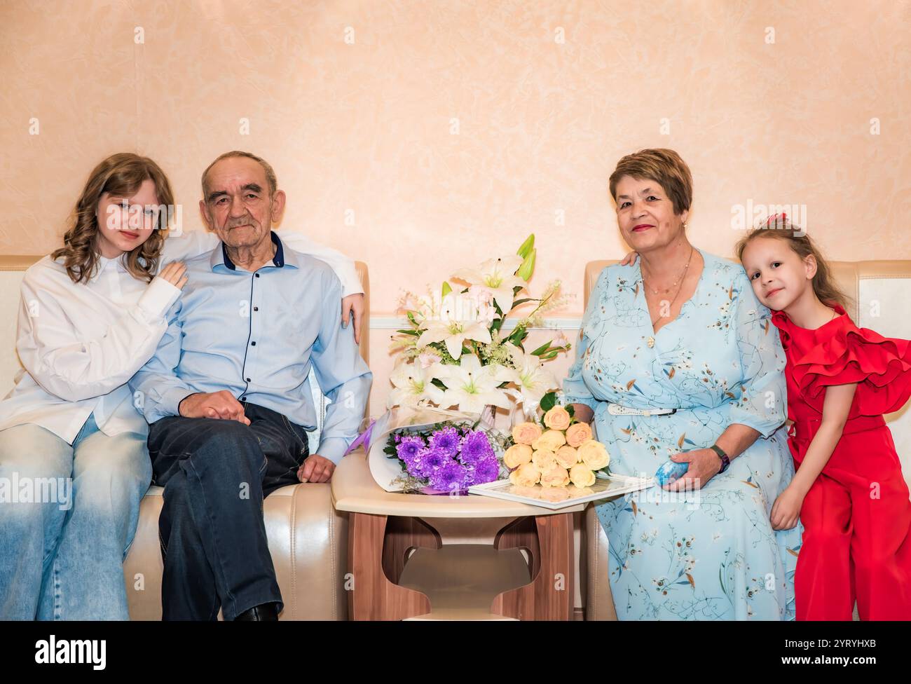 Ein älteres russisches Paar hat gerade im Standesamt geheiratet, neben Blumensträußen in blauer Kleidung. Ihre Enkelinnen, eine Teenager und Stockfoto
