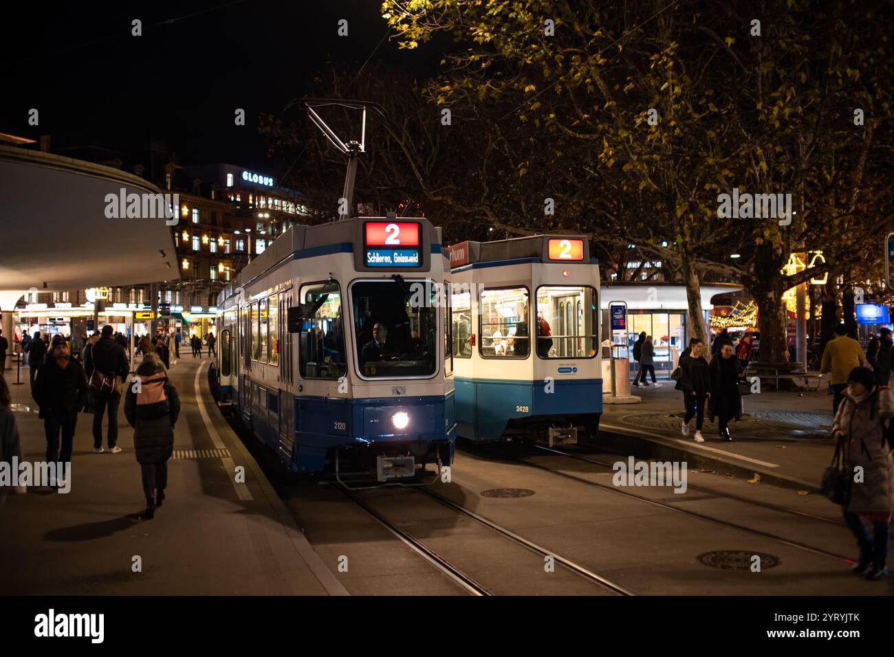 3-12-2024 Zürich, Schweiz. Zwei Straßenbahnen der Linie 2 am Bahnhof Bellevue in der Innenstadt von Zürich bei Nacht. Stockfoto