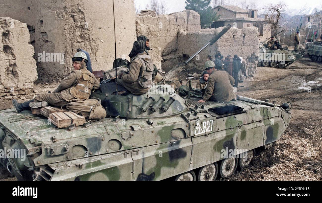 Sowjetische Soldaten reiten am 23. Februar 1988 auf einem Panzer durch ein afghanisches Dorf. Stockfoto