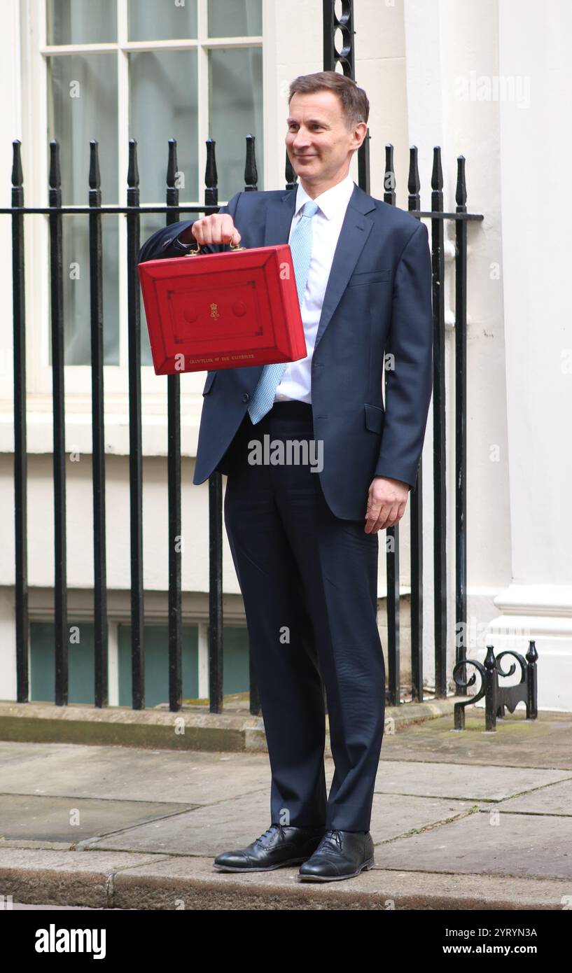 Der britische konservative Kanzler Jeremy Hunt steht mit seinem roten Koffer, als er von der Downing Street in London zum Parlament reist, um den Frühjahrshaushalt im März 2024 zu liefern. Stockfoto