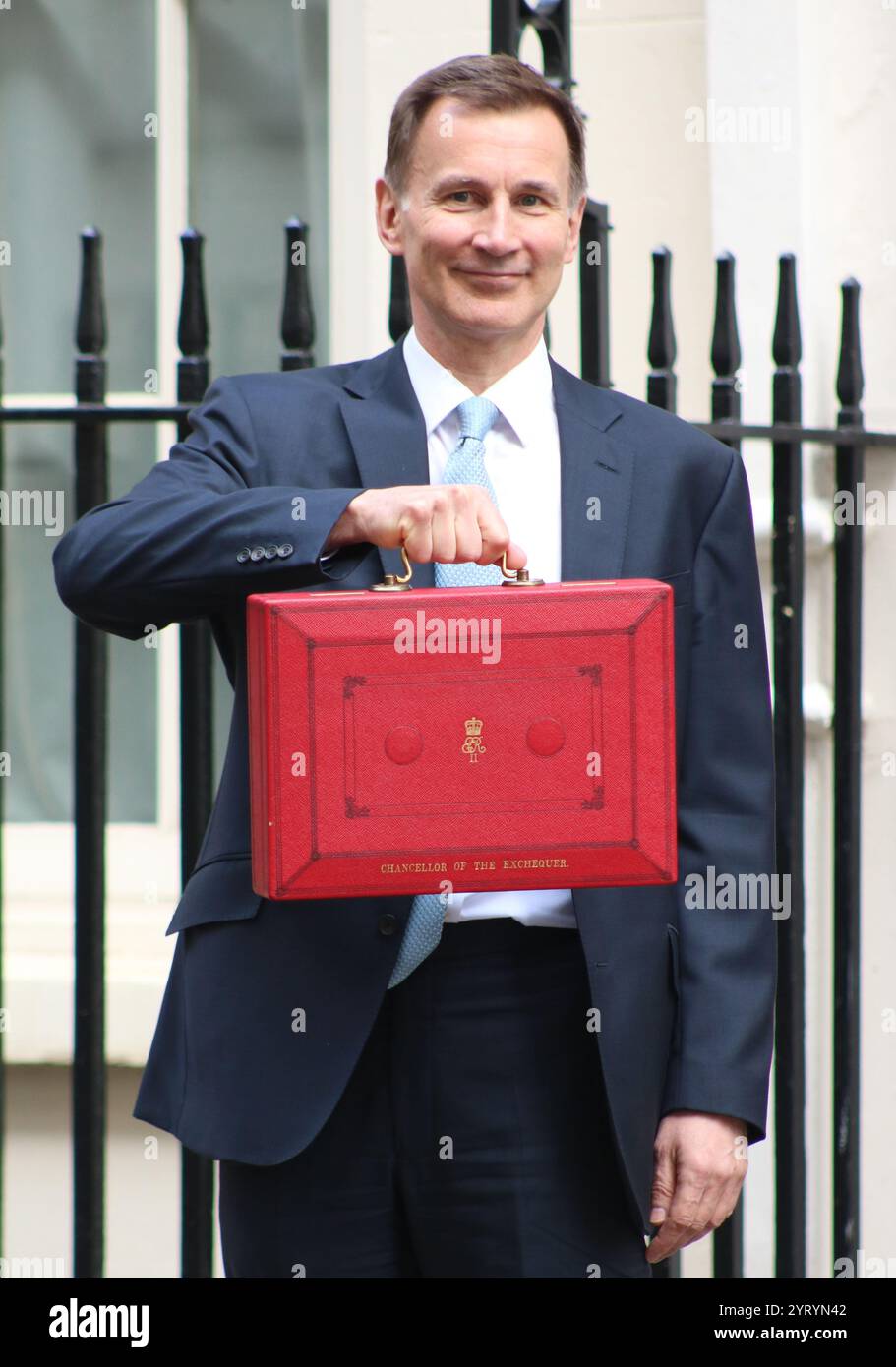 Der britische konservative Kanzler Jeremy Hunt steht mit seinem roten Koffer, als er von der Downing Street in London zum Parlament reist, um den Frühjahrshaushalt im März 2024 zu liefern. Stockfoto