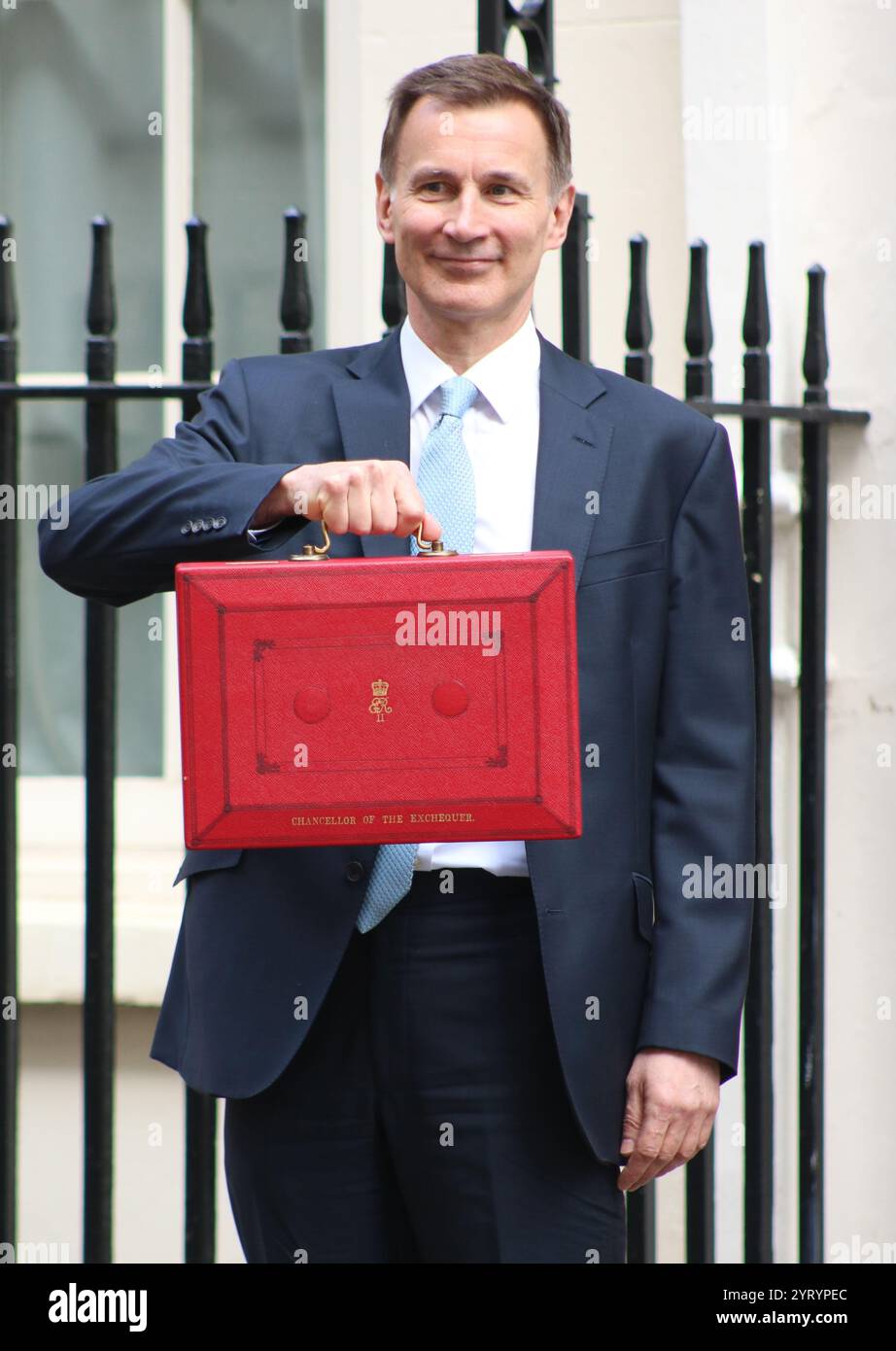 Der britische konservative Kanzler Jeremy Hunt steht mit seinem roten Koffer, als er von der Downing Street in London zum Parlament reist, um den Frühjahrshaushalt im März 2024 zu liefern. Stockfoto