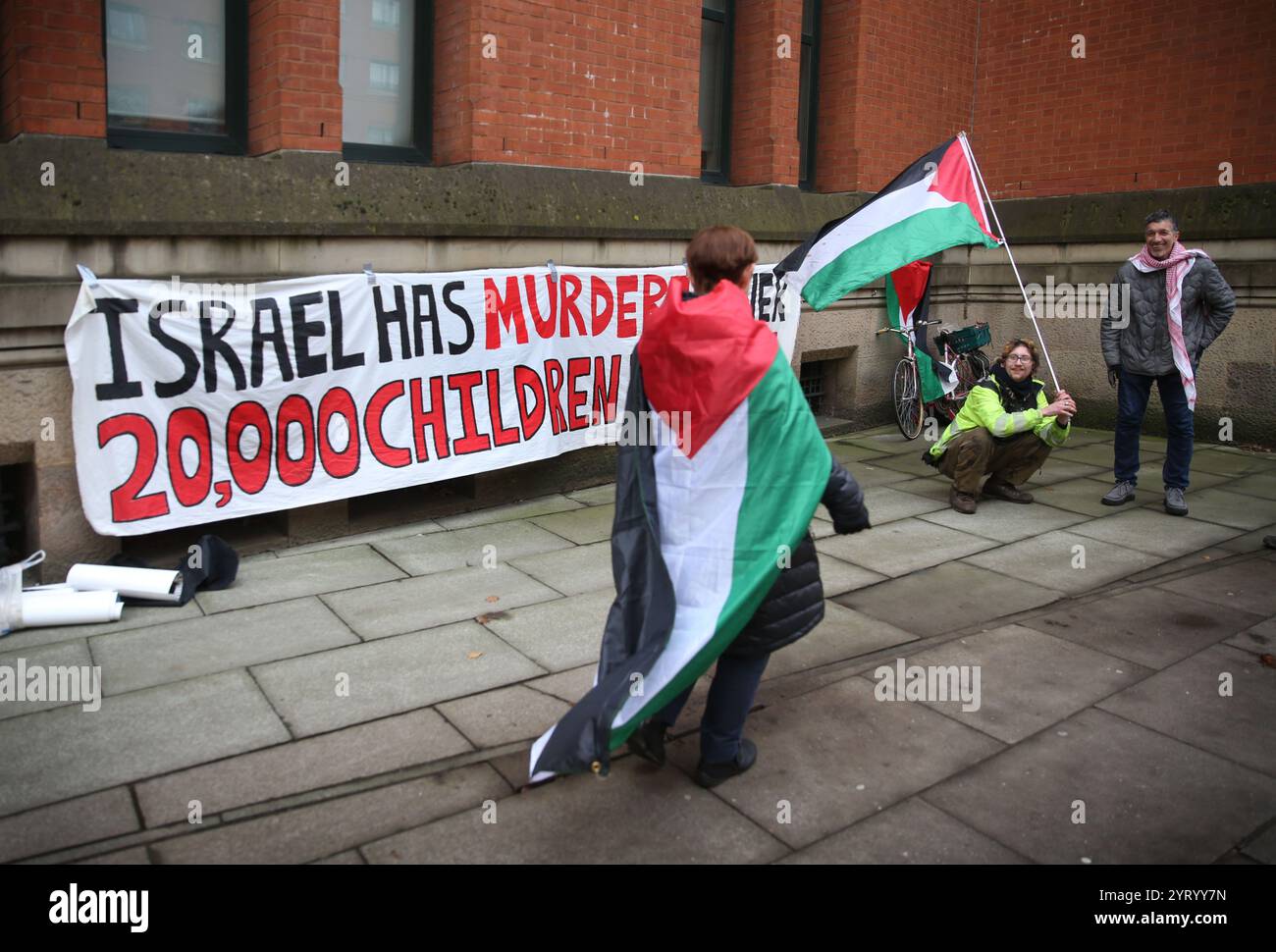 Manchester, Großbritannien. Dezember 2024. Während der Demonstration versammeln sich die Demonstranten vor dem Gericht mit Fahnen und Spruchbändern. Anhänger der Ferranti 2 protestierten vor dem Manchester Crown Court, als der Prozess beginnt. Ihre Maßnahmen und die anhaltende Unterstützung vor Ort führten dazu, dass Elbit Systems im Januar 2022 die Ferranti-Fabrik in Oldham schloss. Quelle: SOPA Images Limited/Alamy Live News Stockfoto